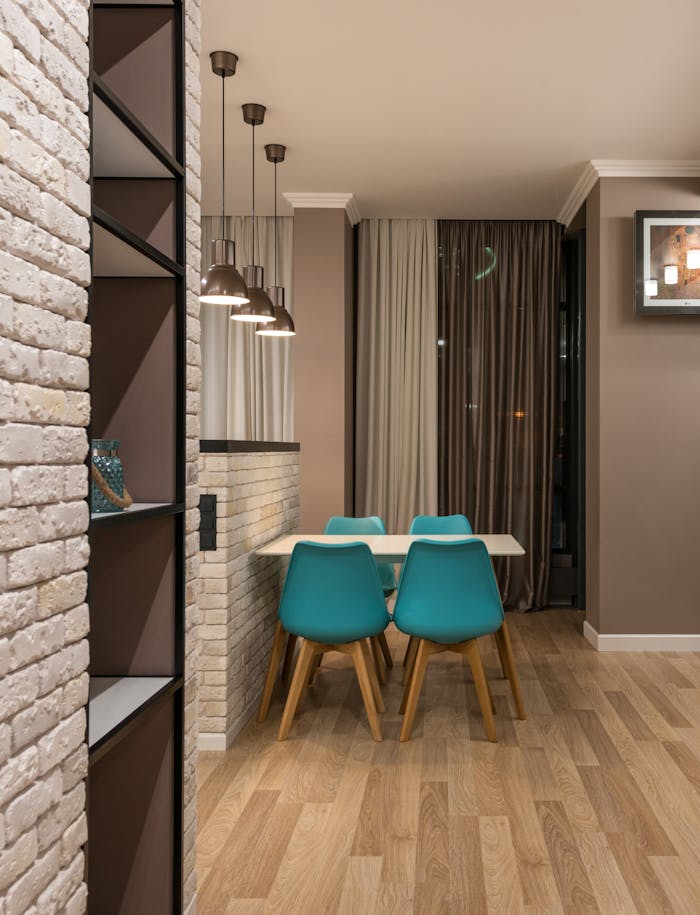 why-choose-us Turquoise chairs at table placed near window with curtains in modern spacious apartment with shelves and decorative white brick wall